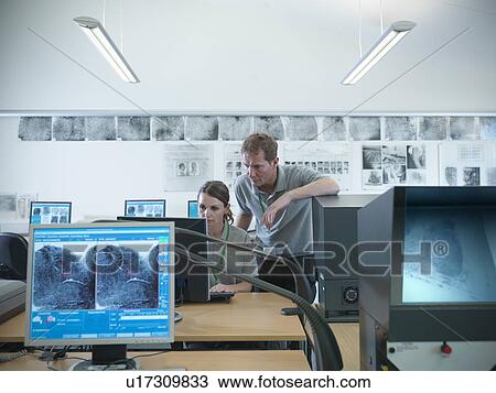Stock Image - Forensic students examining fingerprints. Fotosearch