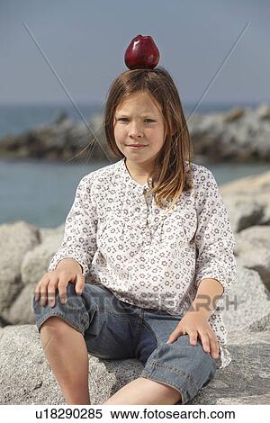 Girl balancing apple on head outdoors View Large Photo Image Stock Photography - Girl balancing apple on head outdoors. Fotosearch