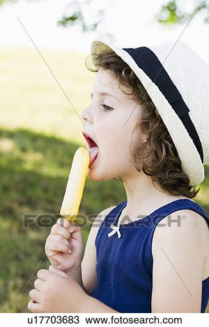 Stock Image - Girl eating popsicle outdoors. Fotosearch