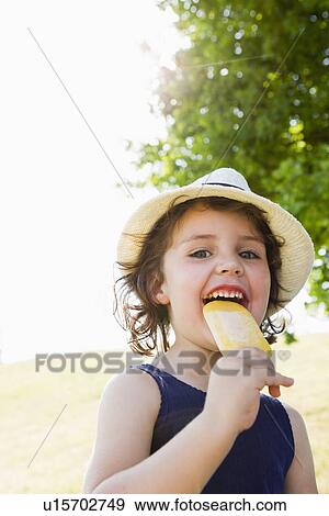 Stock Photo - Girl eating popsicle outdoors. Fotosearch