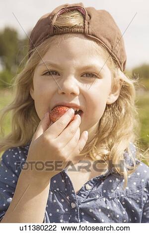 Girl eating strawberry outdoors View Large Photo Image Stock Image - Girl eating strawberry outdoors. Fotosearch