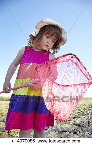 Girl examining fishing net outdoors View Large Photo Image Stock Photograph - Girl examining fishing net outdoors. Fotosearch