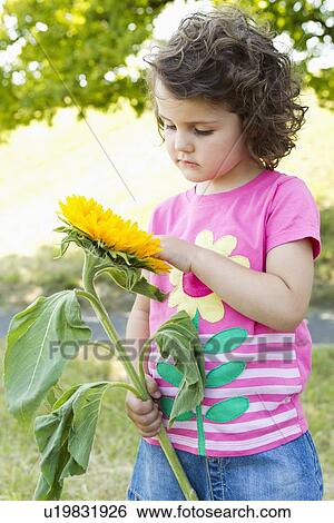Stock Photograph - Girl examining wildflower outdoors. Fotosearch