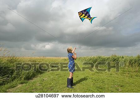 Girl flying kite in rural field View Large Photo Image Stock Photo - Girl flying kite in rural field. Fotosearch