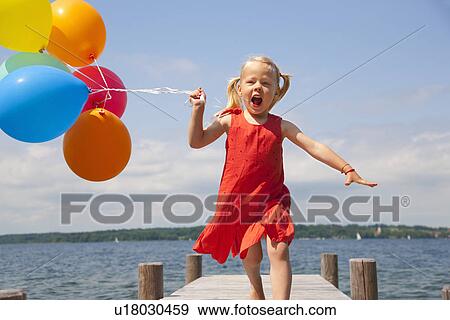 Girl holding balloons on wooden pier View Large Photo Image Stock Photo - Girl holding balloons on wooden pier. Fotosearch
