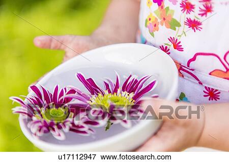 Stock Photo - Girl holding flowers in bowl outdoors. Fotosearch