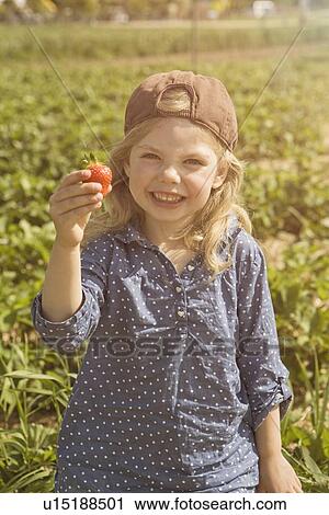 Stock Image - Girl holding fresh picked strawberry. Fotosearch