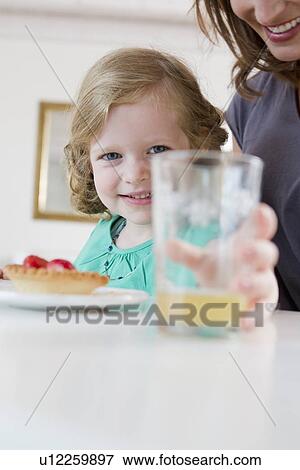 Girl holding glass of juice on table View Large Photo Image Stock Photo - Girl holding glass of juice on table. Fotosearch