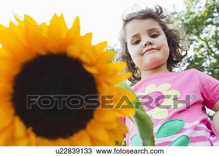 Stock Image - Girl holding wildflower outdoors. Fotosearch