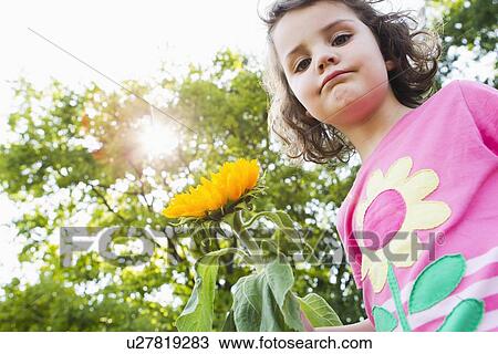 Stock Image - Girl holding wildflower outdoors. Fotosearch