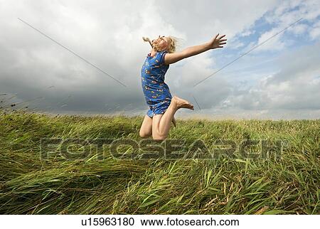 Girl jumping in field of tall grass View Large Photo Image Stock Image - Girl jumping in field of tall grass. Fotosearch