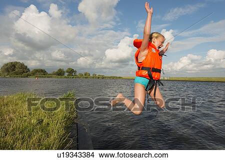 Picture - Girl jumping into rural lake. Fotosearch