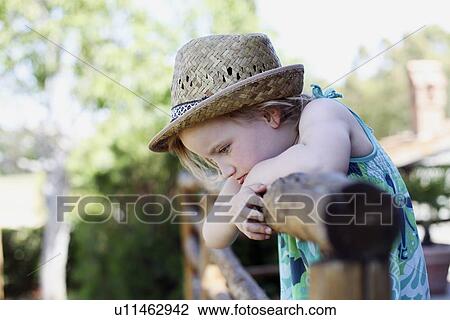 Stock Image - Girl leaning on wooden fence. Fotosearch