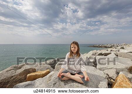 Girl meditating on rocks at beach View Large Photo Image Stock Photography - Girl meditating on rocks at beach. Fotosearch