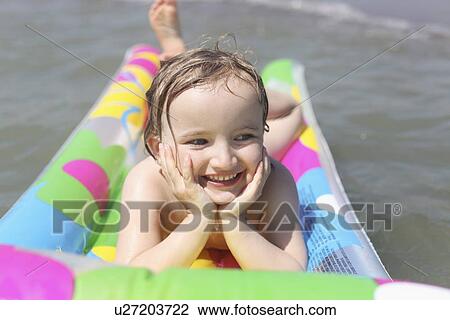 Stock Image - Girl playing on raft in water. Fotosearch