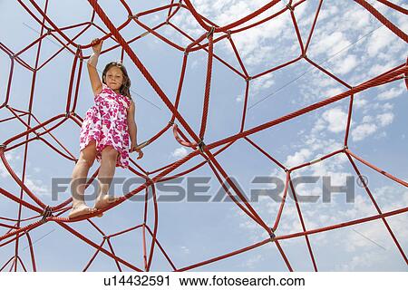 Stock Image - Girl playing on ropes outdoors. Fotosearch