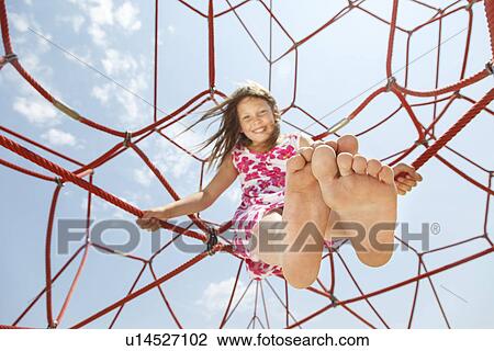 Stock Image - Girl playing on ropes outdoors. Fotosearch