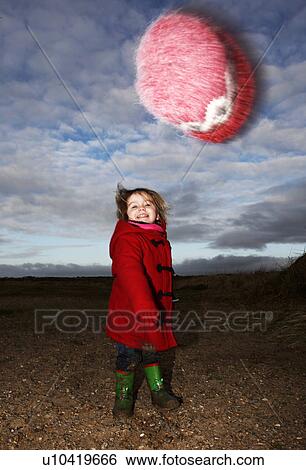 Stock Photograph - Girl playing with fuzzy hat outdoors. Fotosearch