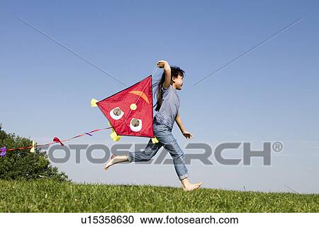 Stock Image - Girl playing with kite outdoors. Fotosearch