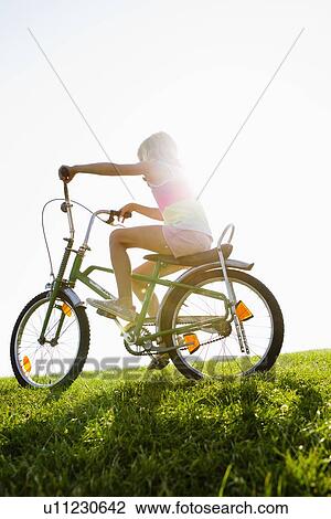 Stock Image - Girl riding bicycle in grass. Fotosearch