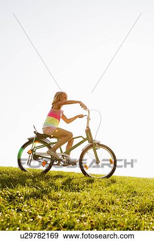 Girl riding bicycle in grass View Large Photo Image Stock Photo - Girl riding bicycle in grass. Fotosearch