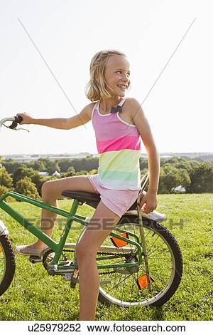 Girl sitting on bicycle in grass View Large Photo Image Stock Image - Girl sitting on bicycle in grass. Fotosearch