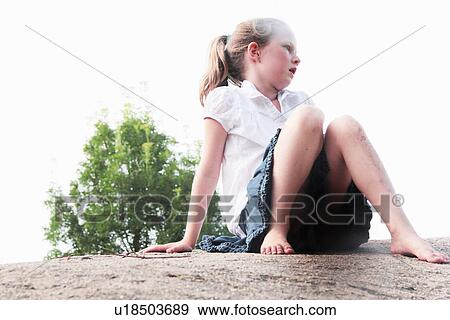 Stock Photo - Girl sitting on stone wall. Fotosearch
