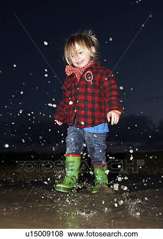 Stock Photo - Girl splashing in puddle at night. Fotosearch
