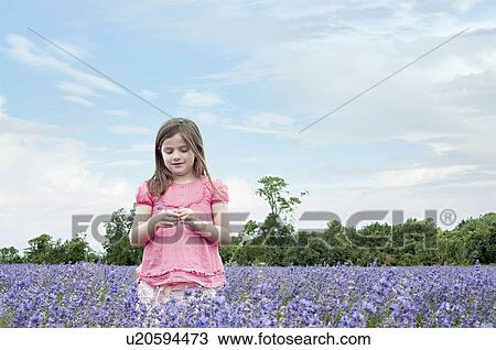Stock Image - Girl standing in field of flowers. Fotosearch