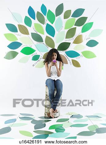 Girl using cell phone by tree on wall View Large Photo Image Stock Image - Girl using cell phone by tree on wall. Fotosearch