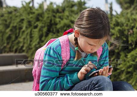 Stock Photo - Girl using cell phone on steps outdoors. Fotosearch