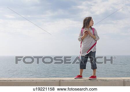Girl walking on stone wall by water View Large Photo Image Stock Photo - Girl walking on stone wall by water. Fotosearch