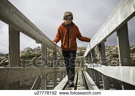 Stock Image - Girl walking on wooden foot bridge. Fotosearch
