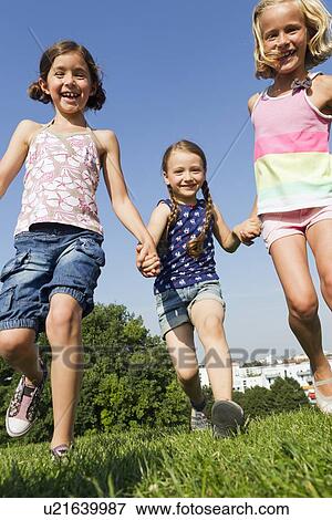 Stock Photo - Girls running together in field. Fotosearch
