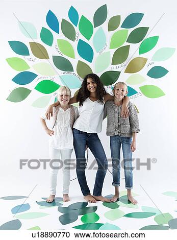 Girls standing under tree on wall View Large Photo Image Stock Image - Girls standing under tree on wall. Fotosearch