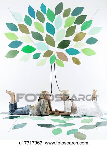 Girls talking under tree on wall View Large Photo Image Stock Photo - Girls talking under tree on wall. Fotosearch