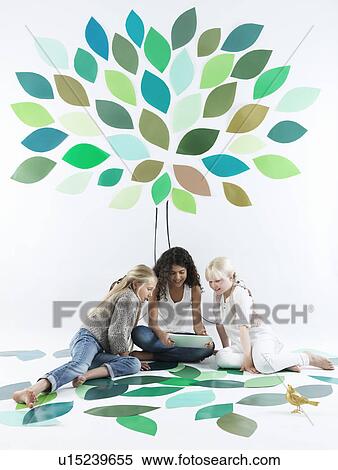 Stock Photography - Girls talking under tree on wall. Fotosearch