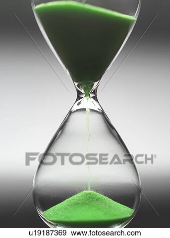 Green sand pouring through hourglass View Large Photo Image Stock Photo - Green sand pouring through hourglass. Fotosearch