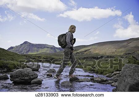 Hiker crossing rocky rural stream View Large Photo Image Stock Image - Hiker crossing rocky rural stream. Fotosearch