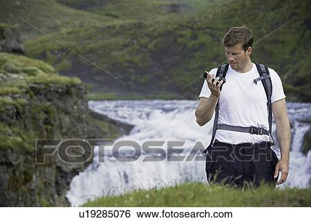 Hiker using cell phone on hillside View Large Photo Image Stock Photograph - Hiker using cell phone on hillside. Fotosearch