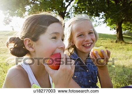 Laughing girls eating apples outdoors View Large Photo Image Stock Image - Laughing girls eating apples outdoors. Fotosearch