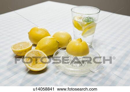 Stock Image - Lemons, juicer and glass of water. Fotosearch