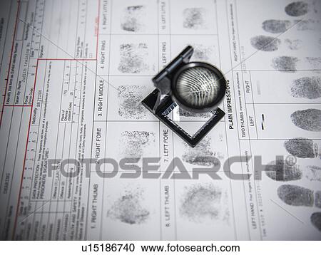 Stock Image - Loupe over fingerprints on arrest form. Fotosearch