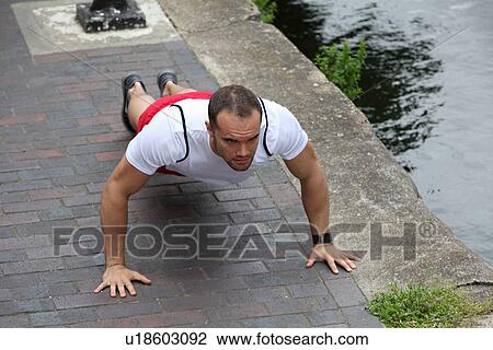Stock Image - Man doing push ups on city street. Fotosearch