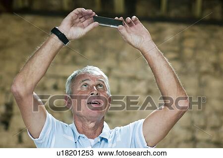 Man examining cell phone indoors View Large Photo Image Stock Image - Man examining cell phone indoors. Fotosearch