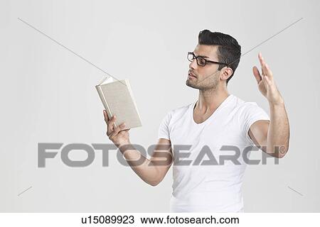 Stock Image - Man gesturing and reading book. Fotosearch