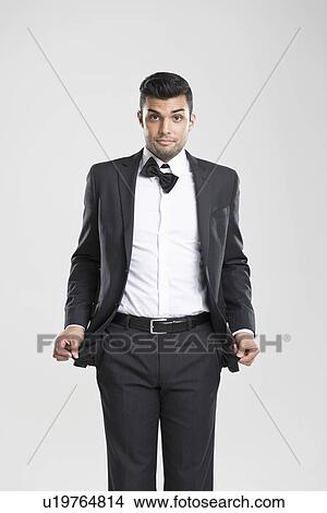 Picture - Man in tuxedo pulling at empty pockets. Fotosearch