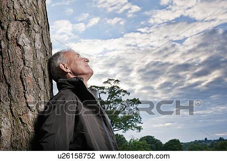 Man leaning against tree outdoors View Large Photo Image Stock Image - Man leaning against tree outdoors. Fotosearch