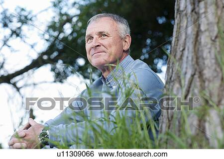 Stock Photograph - Man leaning against tree. Fotosearch