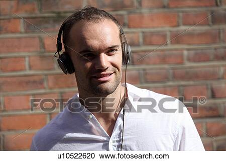 Stock Image - Man listening to headphones outdoors. Fotosearch